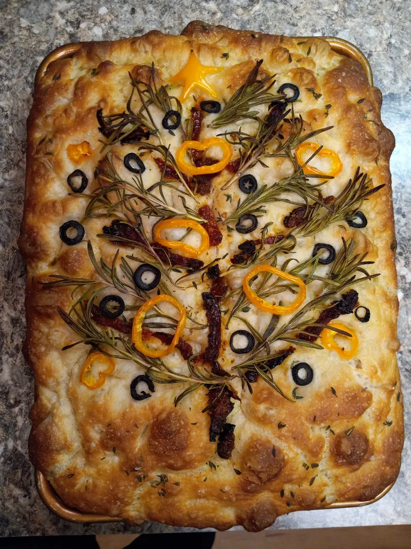 focaccia decorated as a garden with rosemary, peppers and olives