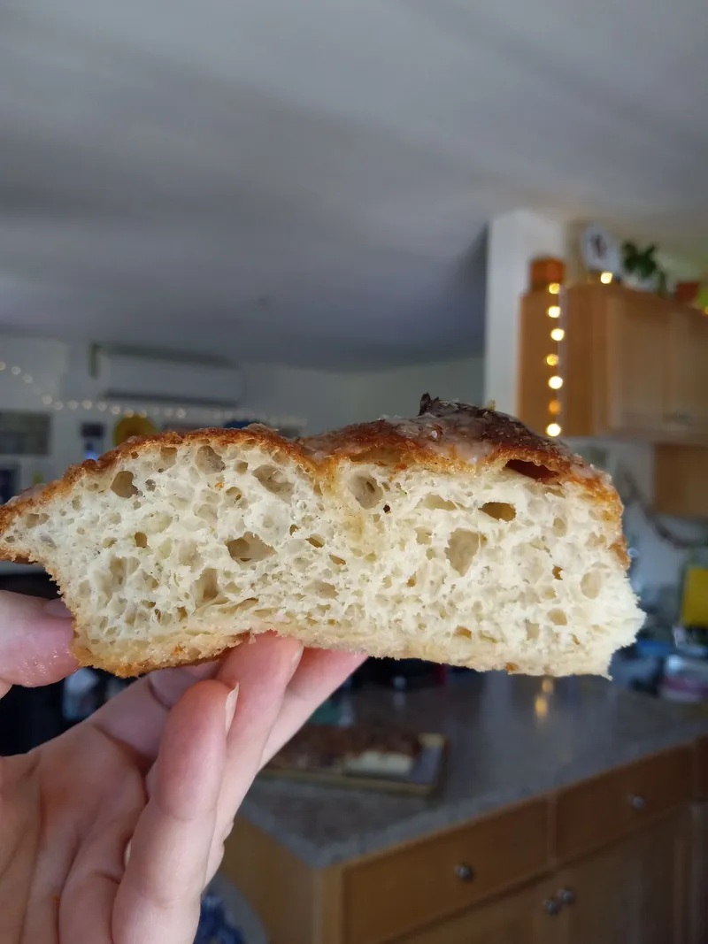 a slice of focaccia held up to show its open crumb