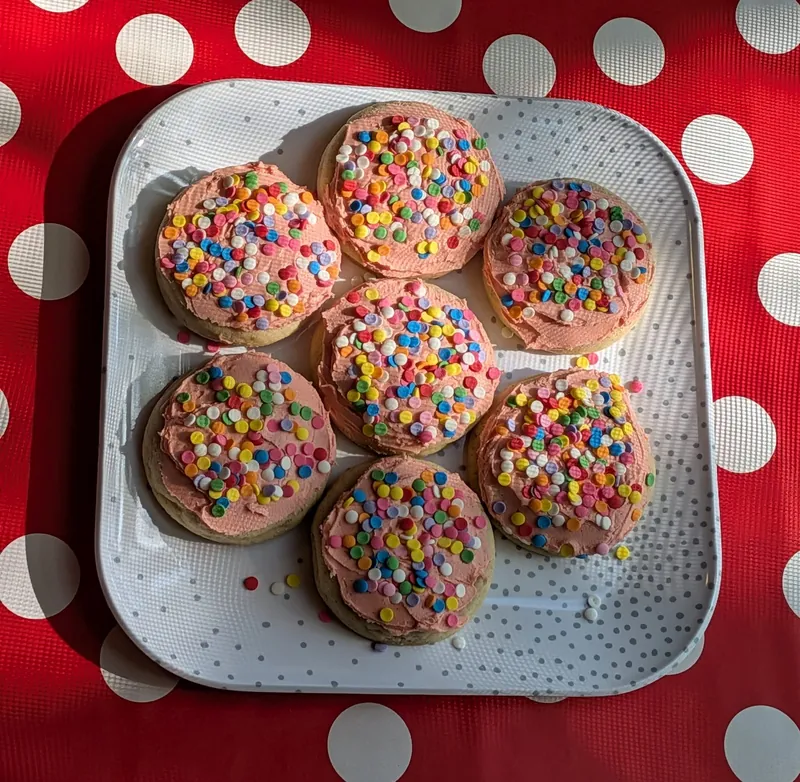 frosted vanilla bean sugar cookies with rainbow sprinkles on a red polka-dot tablecloth