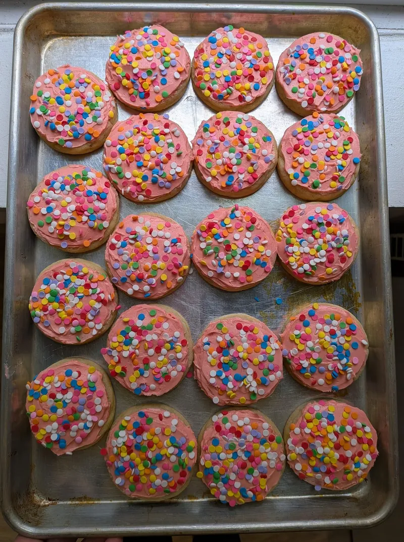 a full tray of frosted vanilla bean sugar cookies with rainbow sprinkles