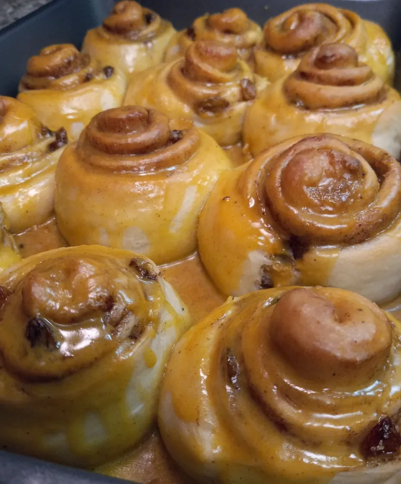 cinnamon rolls in a pan under a thick orange glaze