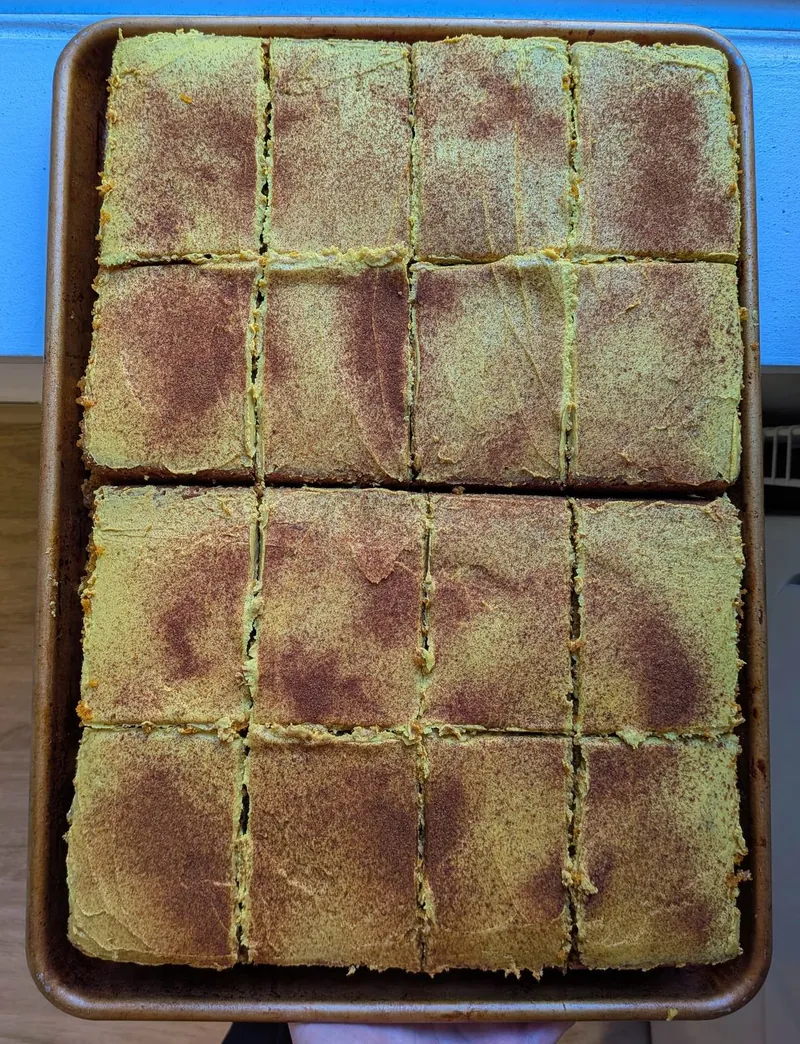 a sheet cake cut in squares, its frosting dusted with spice