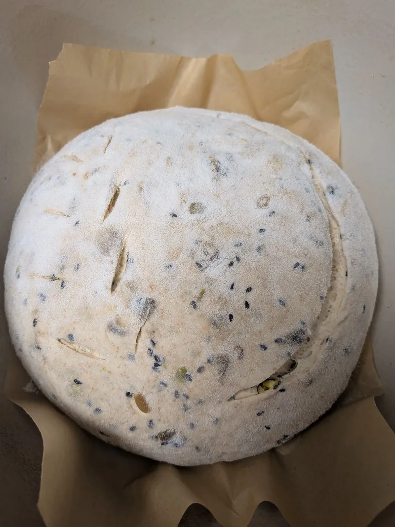 a scored, floured loaf of seeded spelt sourdough with pistachios, before baking