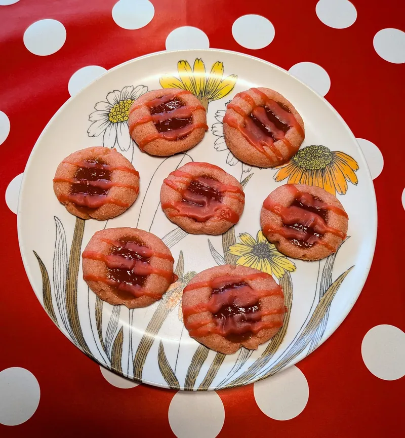 strawberry apricot thumbprint cookies with strawberry icing on a flowered plate