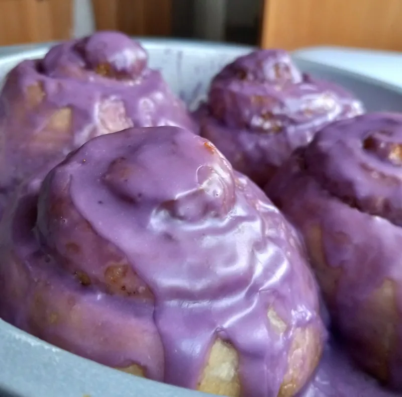ube cinnamon rolls in a pan, under a thick, glossy purple glaze